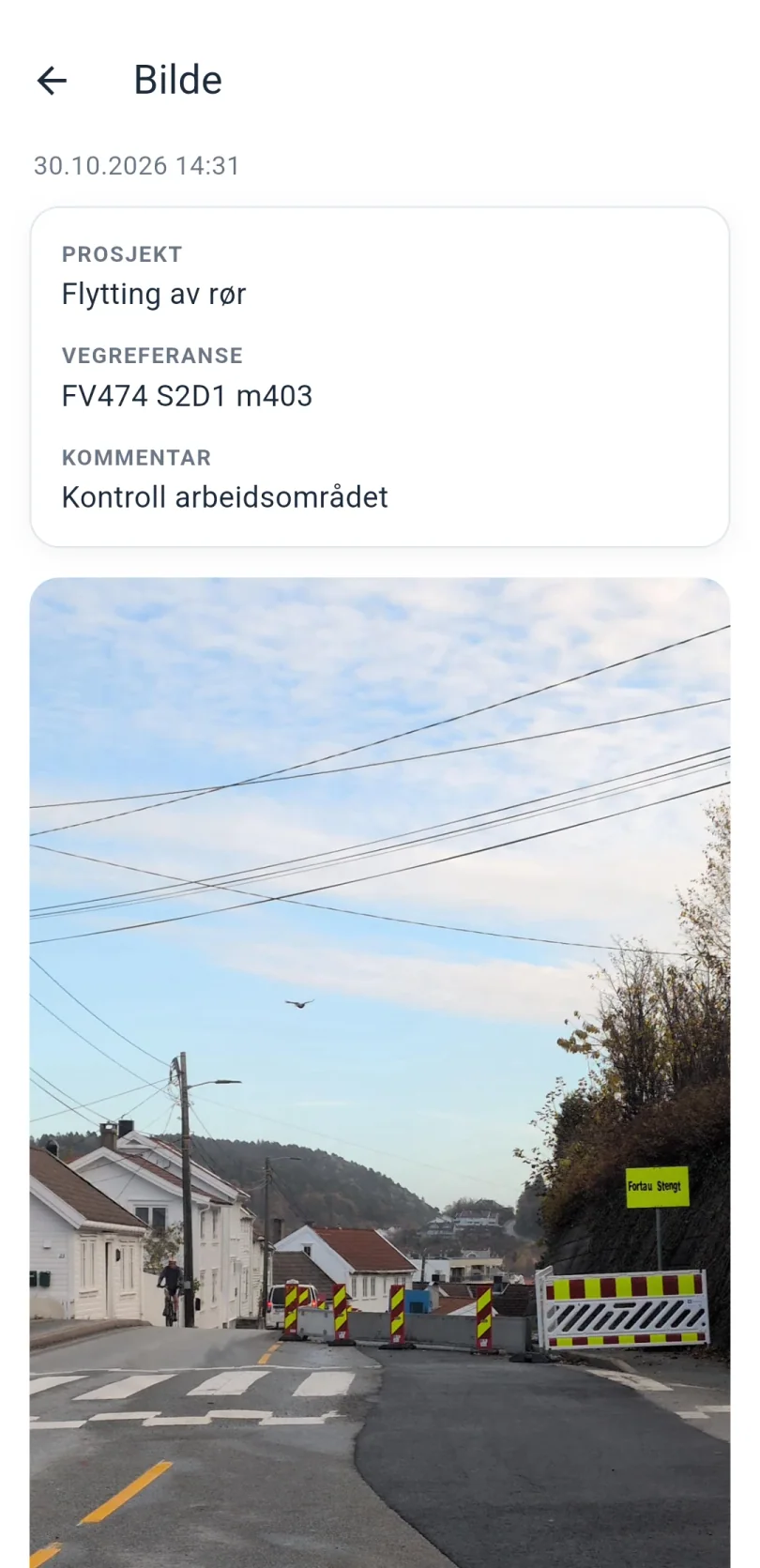 Skjermen Bilde i appen: dato og klokkeslett, prosjektet Flytting av rør, vegreferansen FV474 S2D1 m403, kommentaren Kontroll arbeidsområdet og under det selve bildet av en stengt vei med skilt og sperringer.